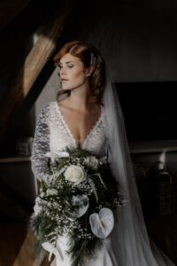 Braut zeigt kurz vor der Hochzeit stolz ihr Brautkleid und Brautstrauß.