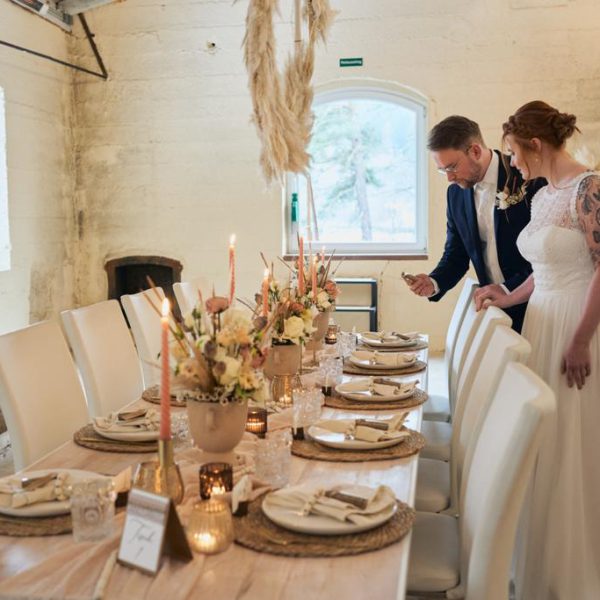Ein Brautpaar schaut sich die vielen Details ihrer Tischdekoration an.