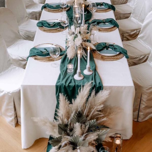 Hochzeitstisch dekoriert im bohoglam-Style in Naturtönen und Smaragdgrün.