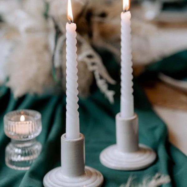 Weiße Kerzenständer auf grünem Samt auf einem Hochzeitstisch.