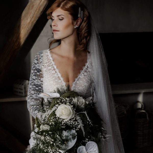 Braut zeigt kurz vor der Hochzeit stolz ihr Brautkleid und Brautstrauß.