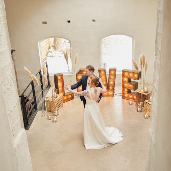 Tanzendes Brautpaar vor einer Kulisse mit Lovebuchstaben und Laternen.