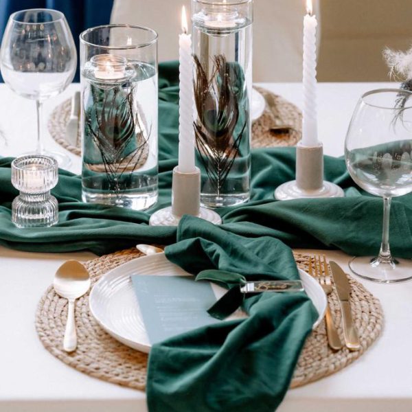 Tischdeko zur Hochzeit in grün mit Pfauenfedern.